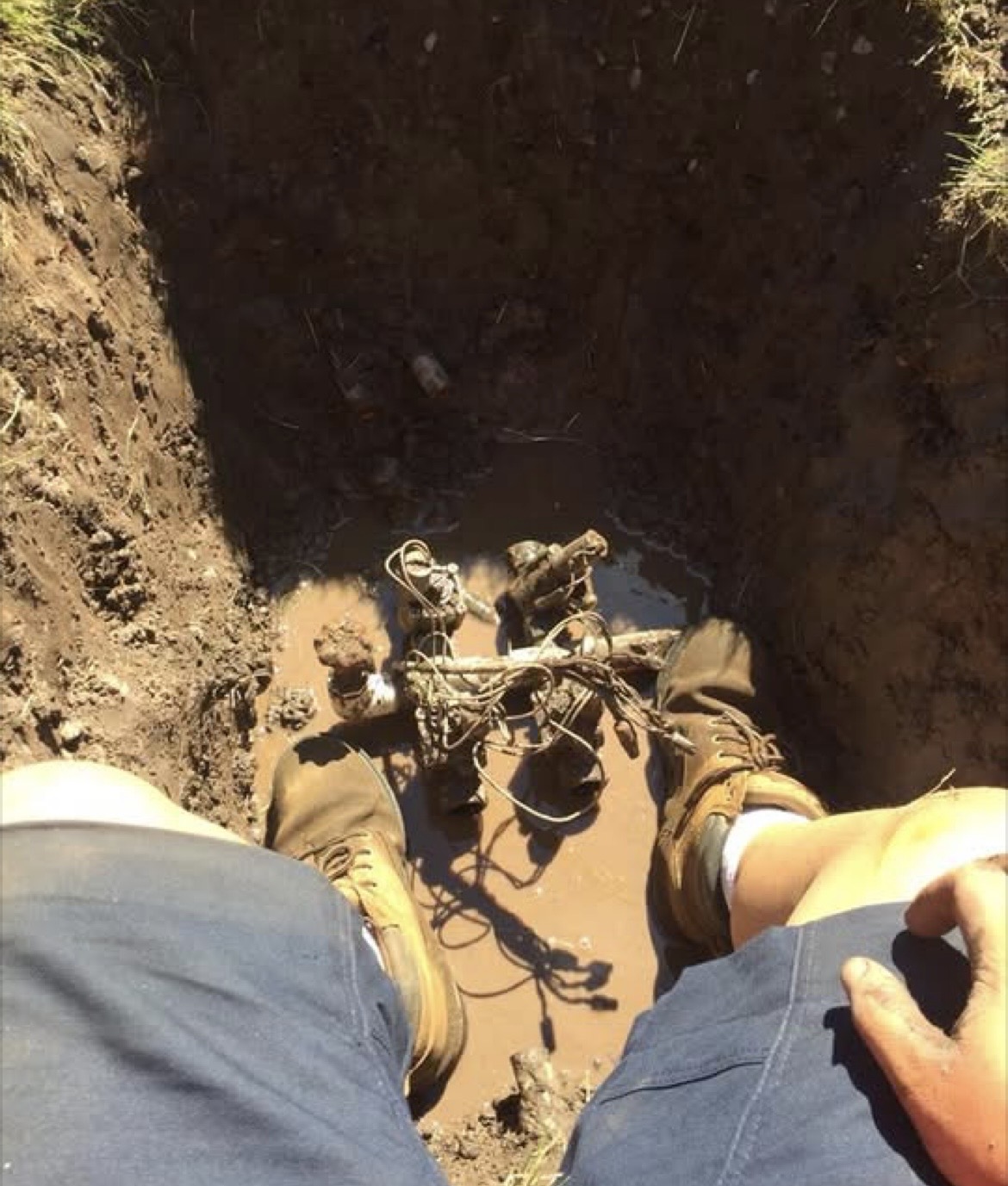 Before: open trench exposing a damaged, tangled valve assembly buried in mud